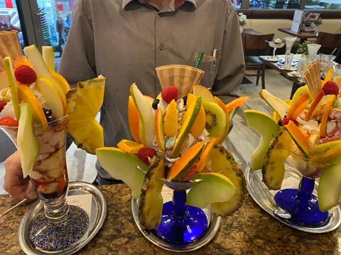 Drei hohe Fruchtbecher mit aufgefächerter Melone, Ananas und Kiwi auf der Theke