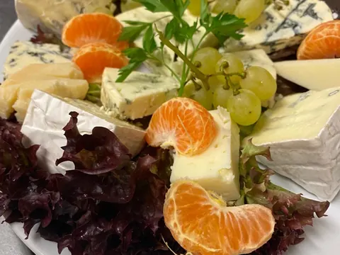 Käseplatte mit Brie, Blauschimmelkäse, Trauben und Mandarinen auf Salat