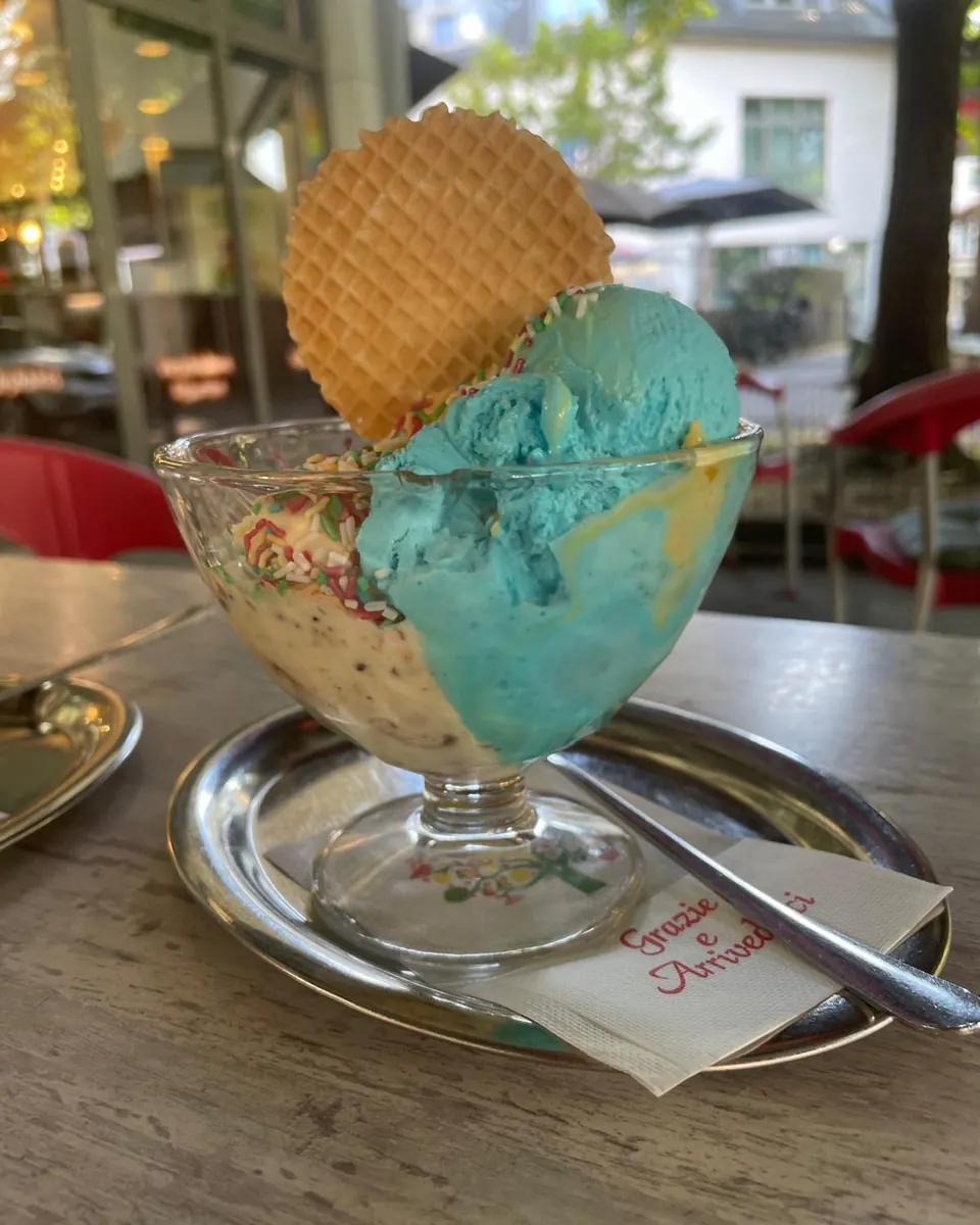 Eisbecher mit blauem Azzurro-Eis, Streuseln und runder Waffel in einer Glasschale