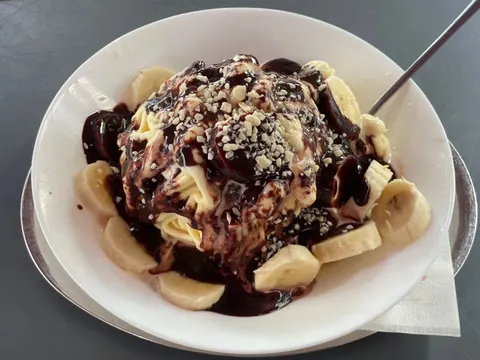 Spaghettieis mit Schokoladensoße, Bananenscheiben und gehackten Nüssen
