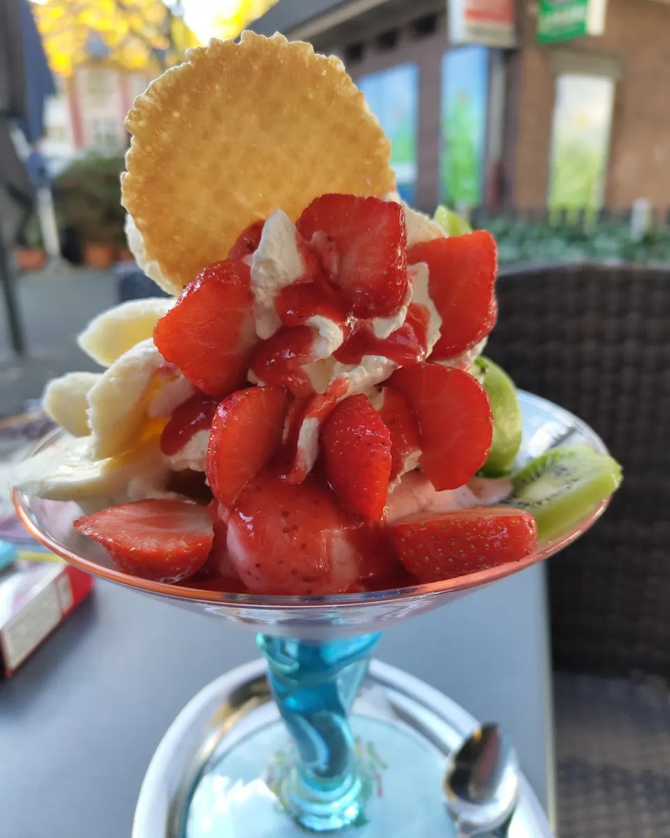 Erdbeerbecher mit frischen Erdbeeren, Sahne und runder Waffel