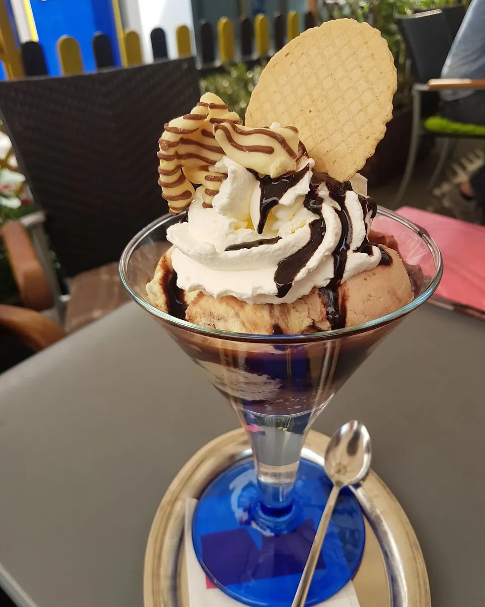 Schokoladenbecher mit Sahne, Schokoladensoße und Waffel auf dem Terrassentisch