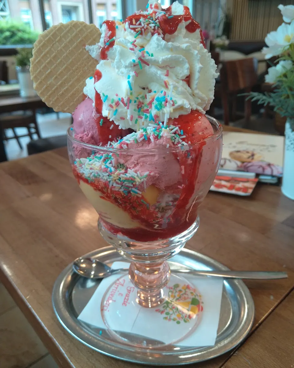 Erdbeerbecher mit Erdbeereis, Sahne, bunten Streuseln und Waffel