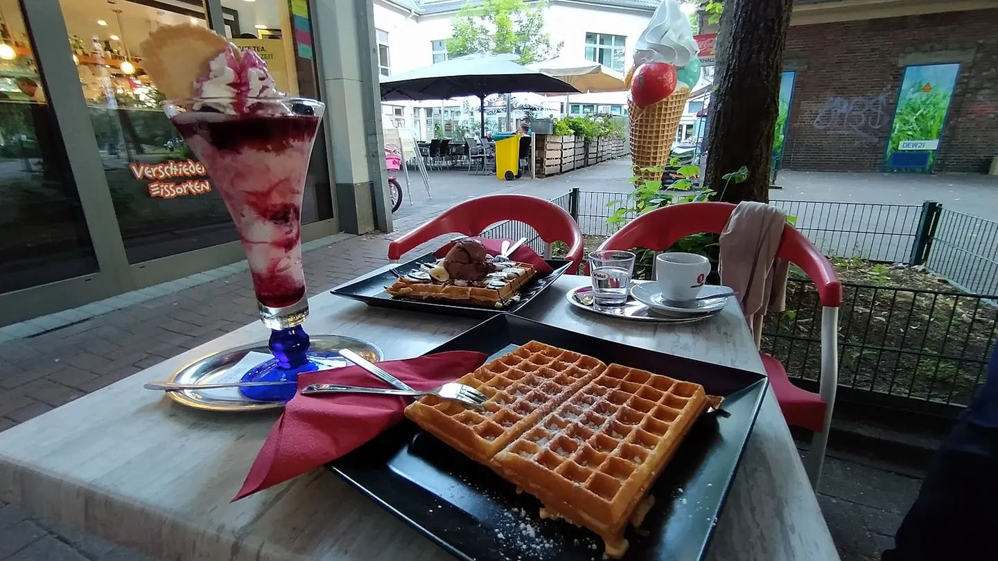 Terrassentisch mit hohem Fruchtbecher, zwei Waffeln und Espresso