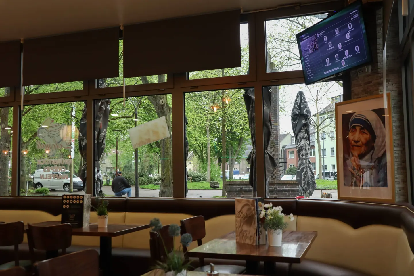 Sitzbereich an der Fensterfront mit Polsterbank und Blumen auf den Tischen